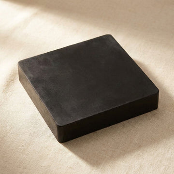 Black rubber bench block, 6 x 6 x 1 inch, square, lying on a linen cloth