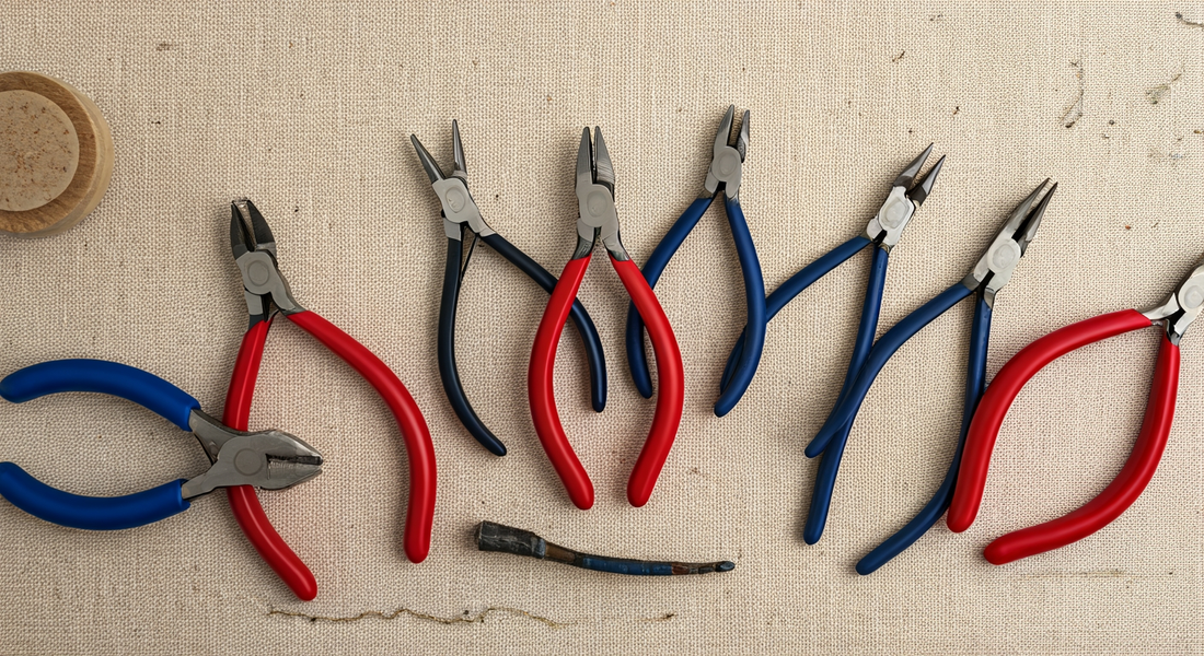 Seven jeweller's pliers fanned out on cream linen — round, chain, flat, bent, parallel and specialty