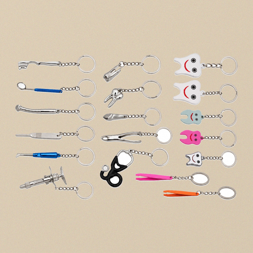 Assortment of miniature dental and medical instrument keyring charms — tooth, syringe, forceps, dental mirror, handpiece and stethoscope designs on a cream background.