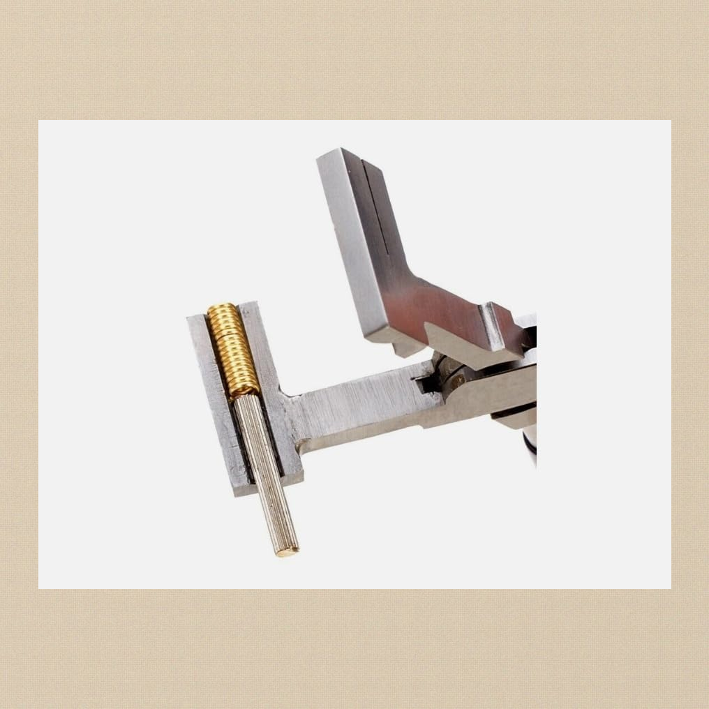 Coil cutting pliers with the jaws open and a gold-coloured wire coil on a knurled mandrel in the jaw channel, ready for cutting jump rings