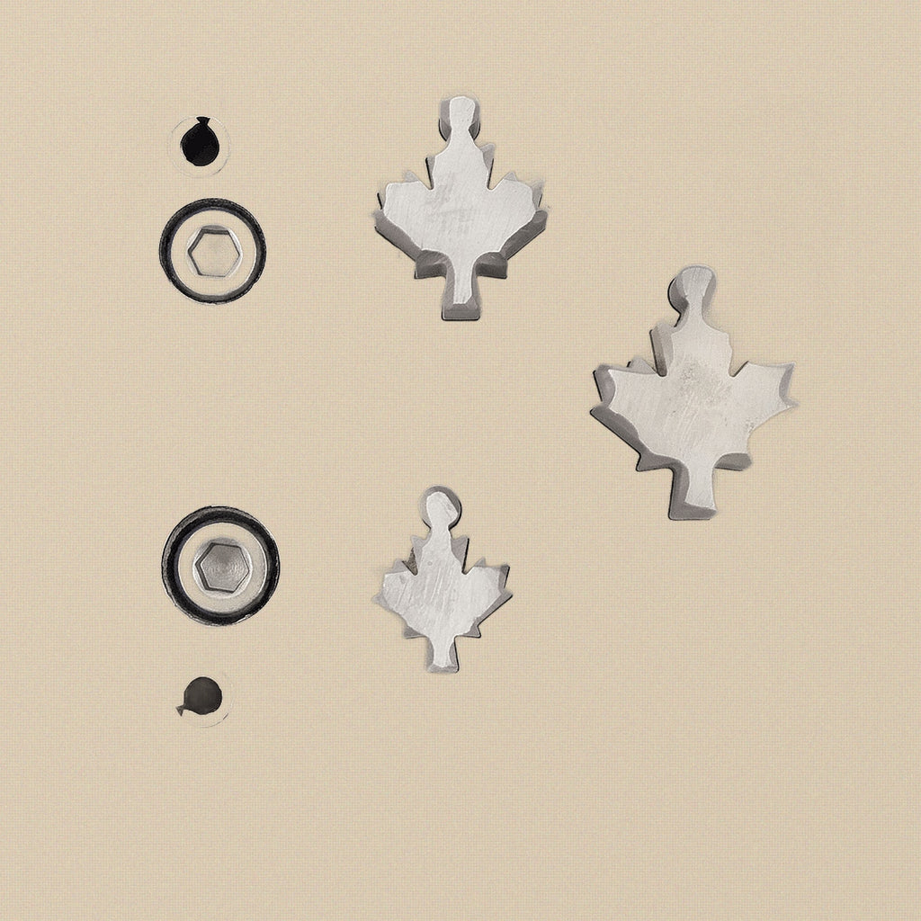 Hardened steel disc cutter block with three maple leaf shaped punches arranged neatly beside it.