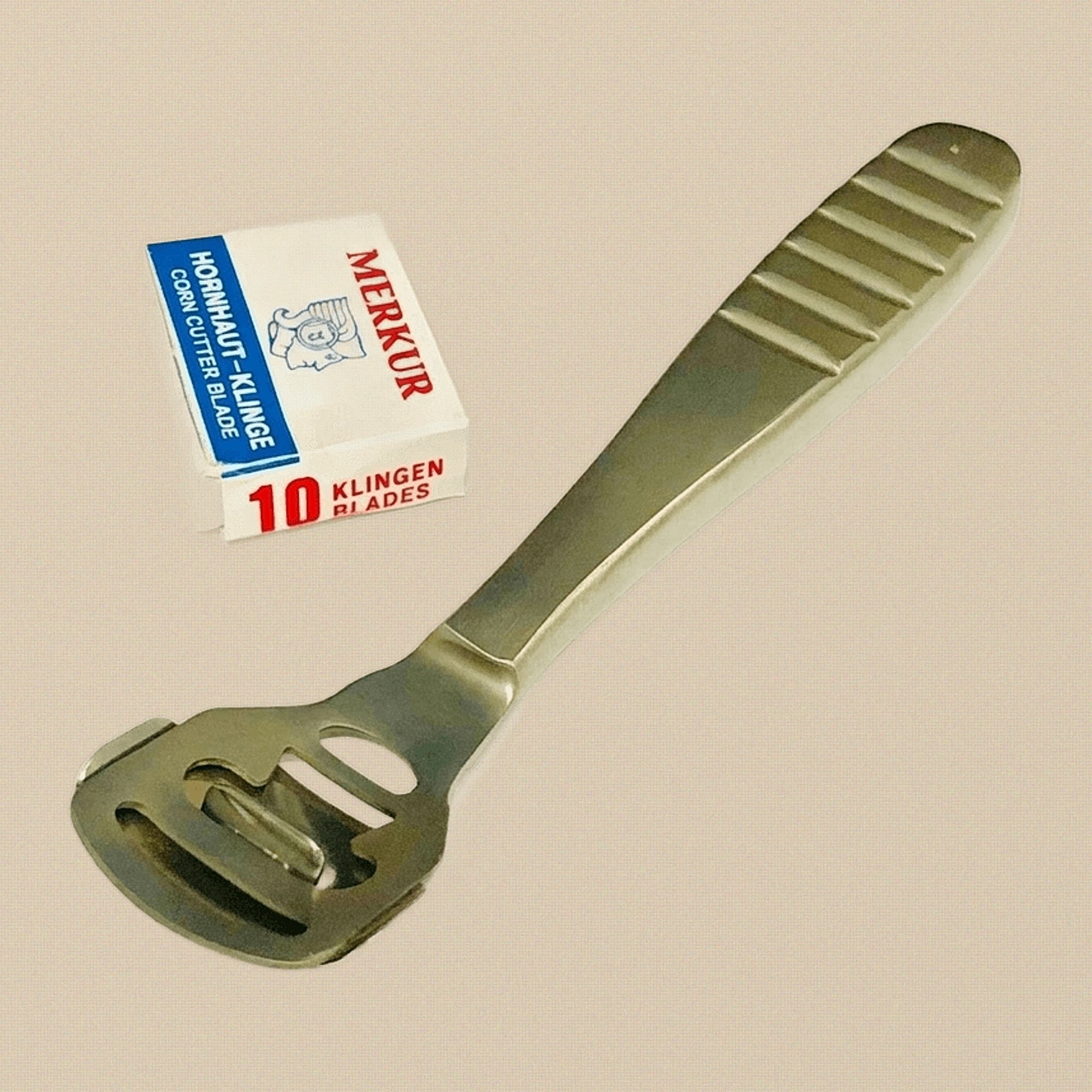 Stainless steel callus and corn plane shaver for foot care, shown with its two-part head slightly open.