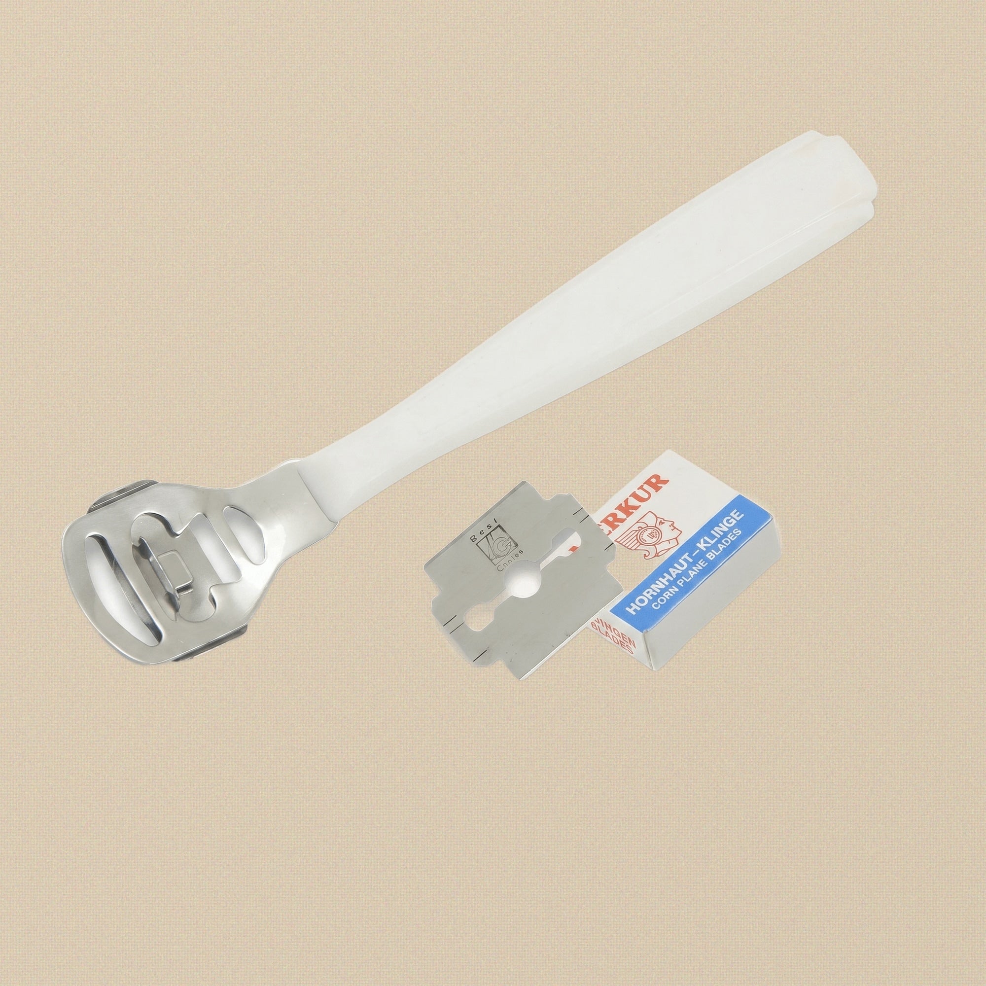A pedicure corn plane with a white plastic handle and stainless steel head, shown with a pack of 10 replacement blades.