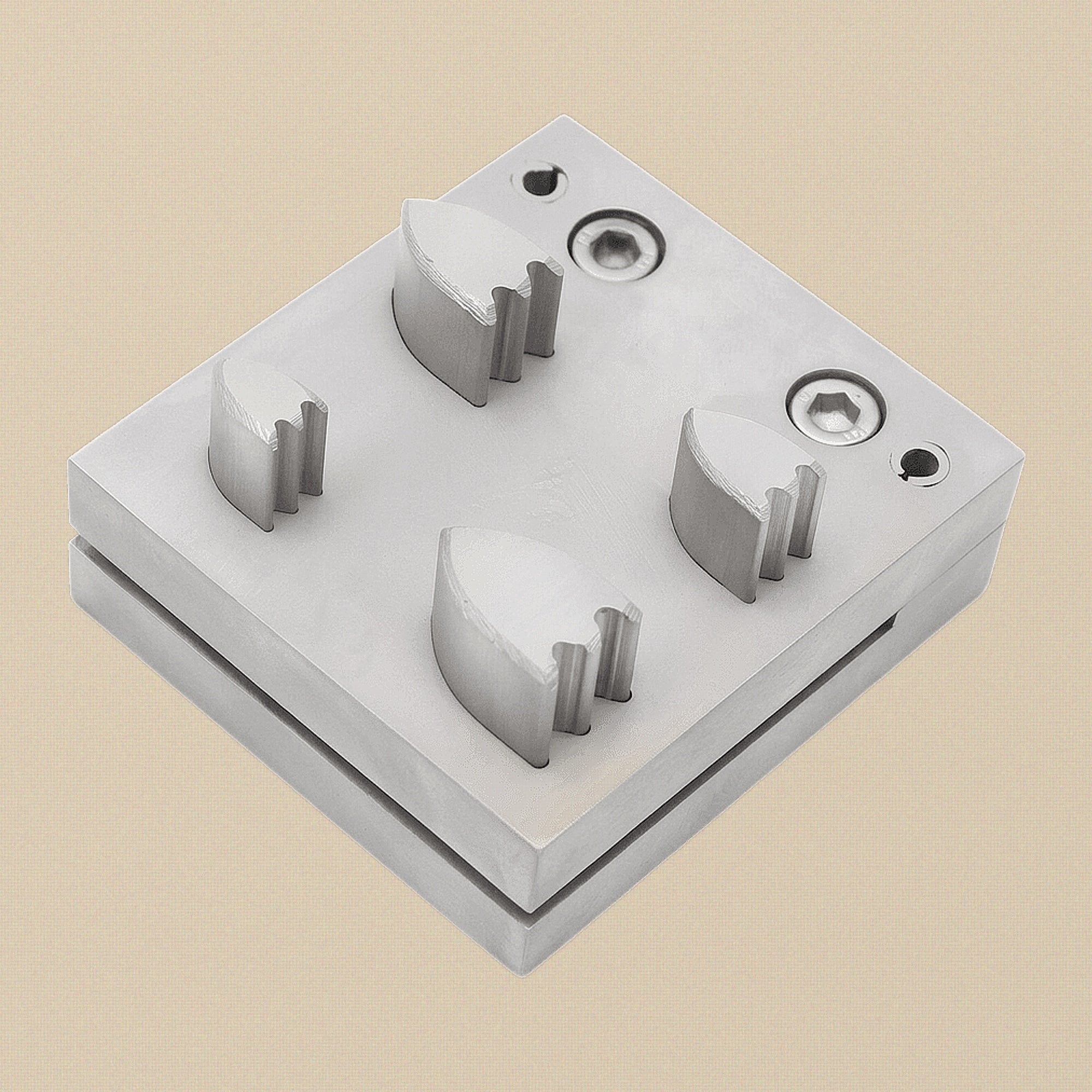 Top-down view of the steel die block showing the four shield-shaped apertures.