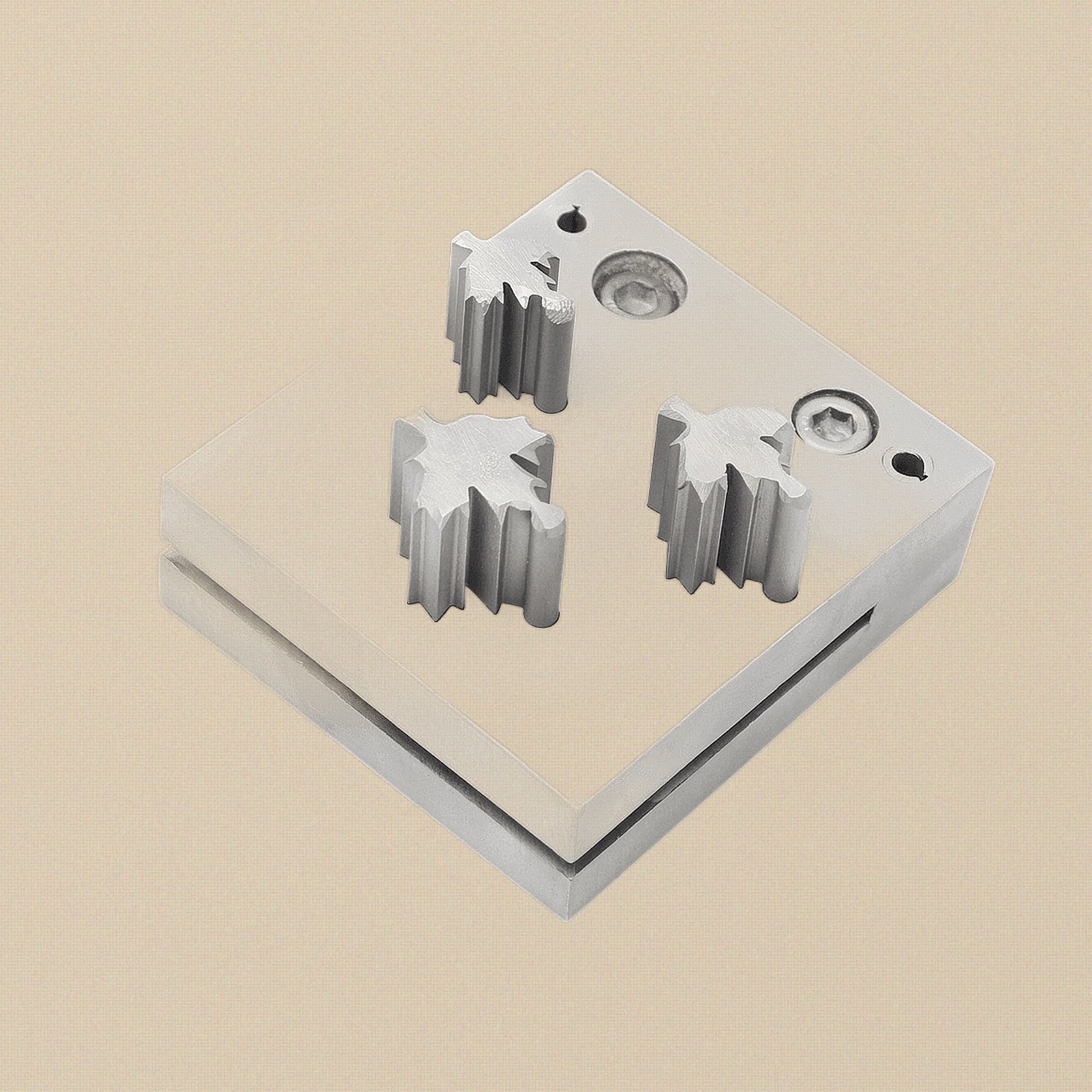 Close-up of the three maple leaf punch cutting heads showing the sharp, machined edges.