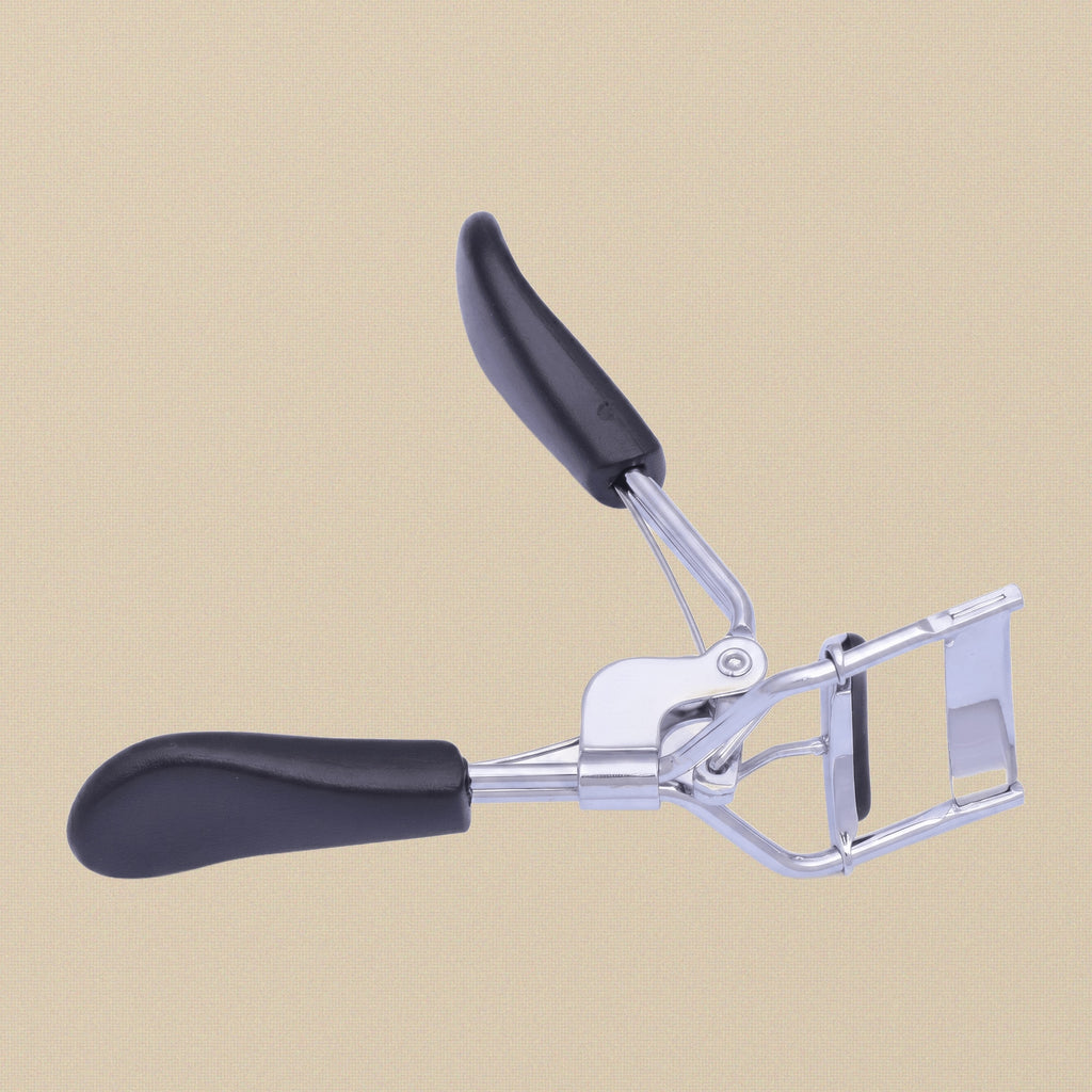 Eyelash curler held in hand to demonstrate the ergonomic grip and size.