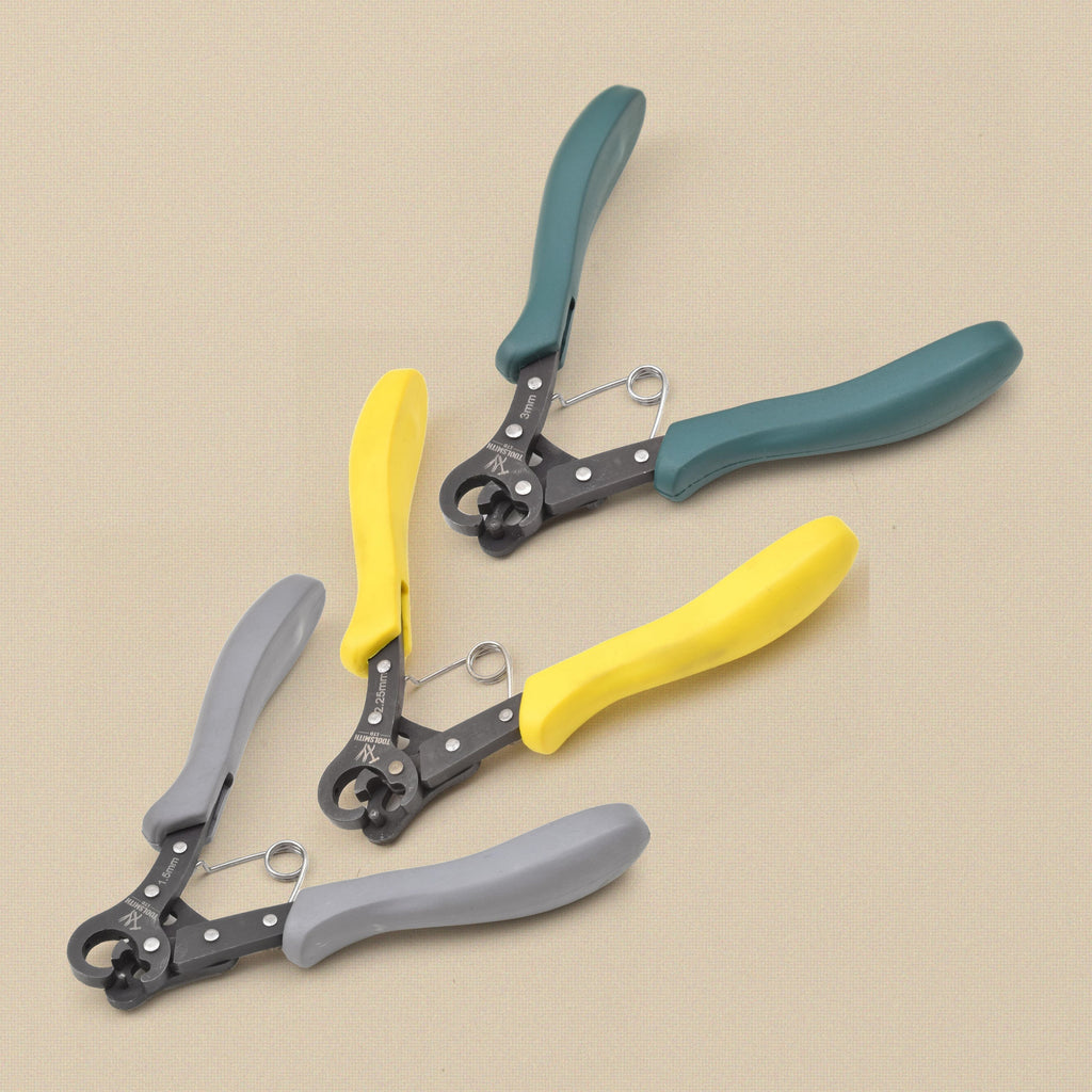 Set of three one-step looper pliers fanned out on a cream background: 1.5 mm with grey grips, 2.25 mm with yellow grips and 3 mm with green grips