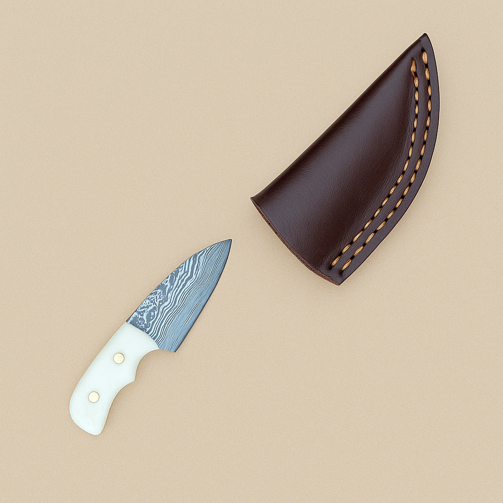 Miniature Damascus skinner knife with bone handle beside its dark leather sheath, on a plain tan background