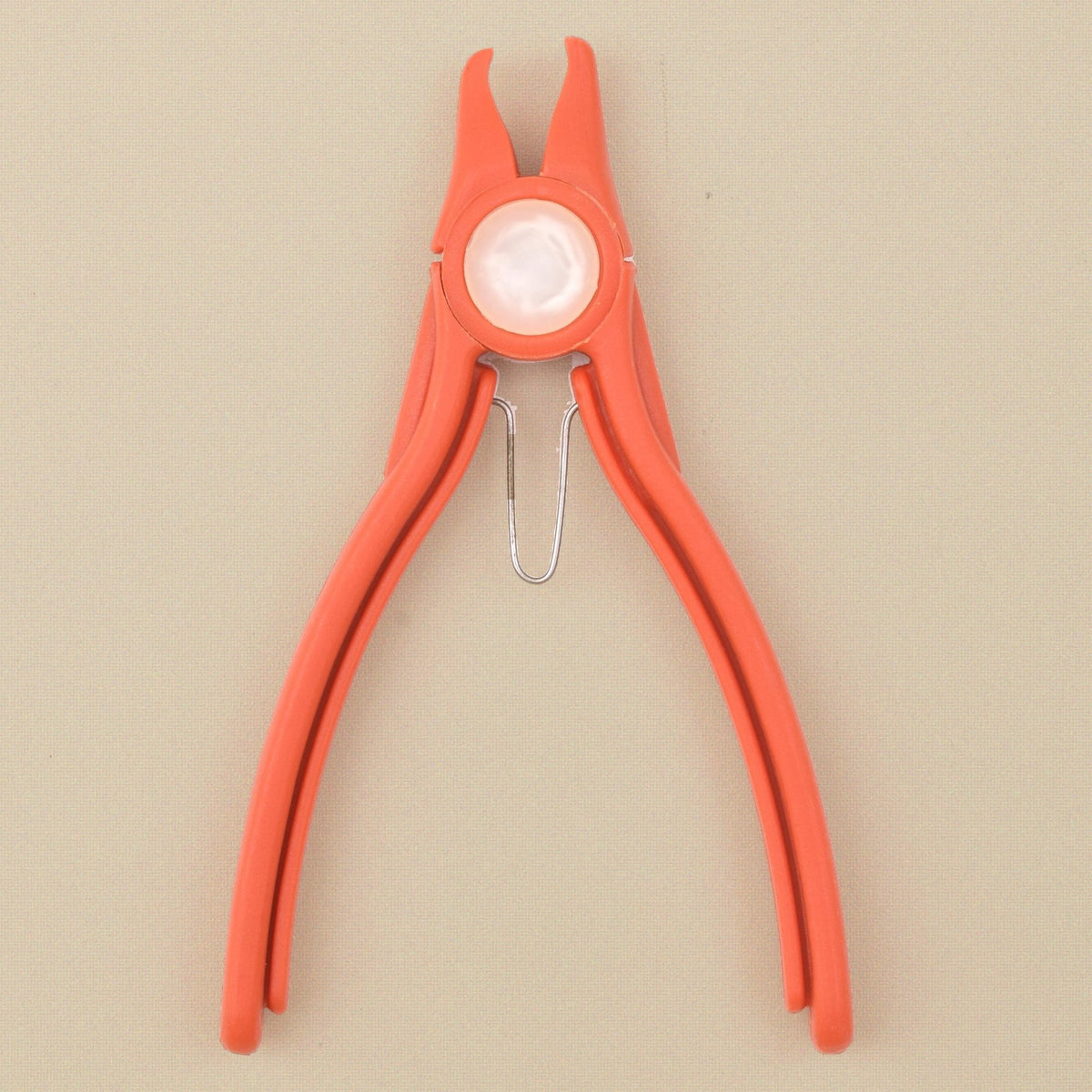 Orange plastic stone setting pliers standing, jaws upward