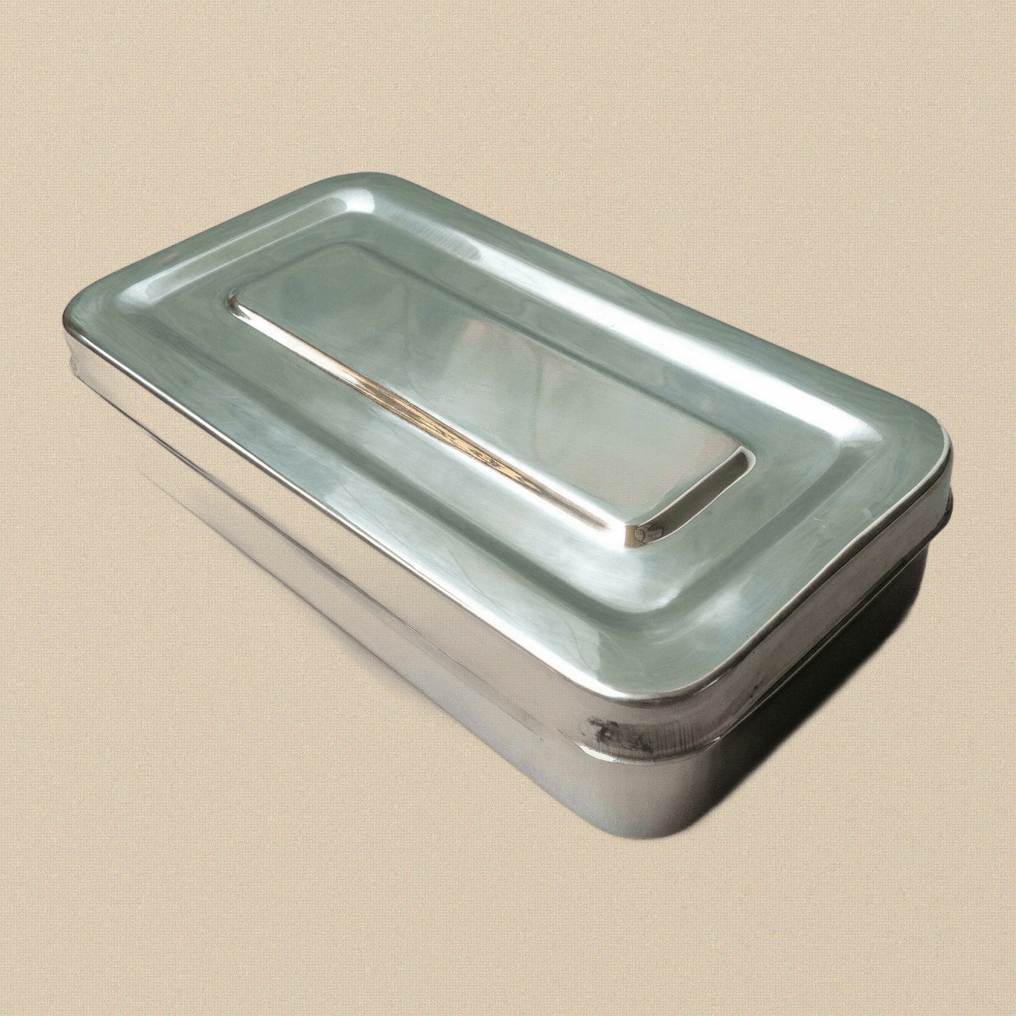 Open stainless steel instrument sterilisation box, showing the polished interior and separate lid.