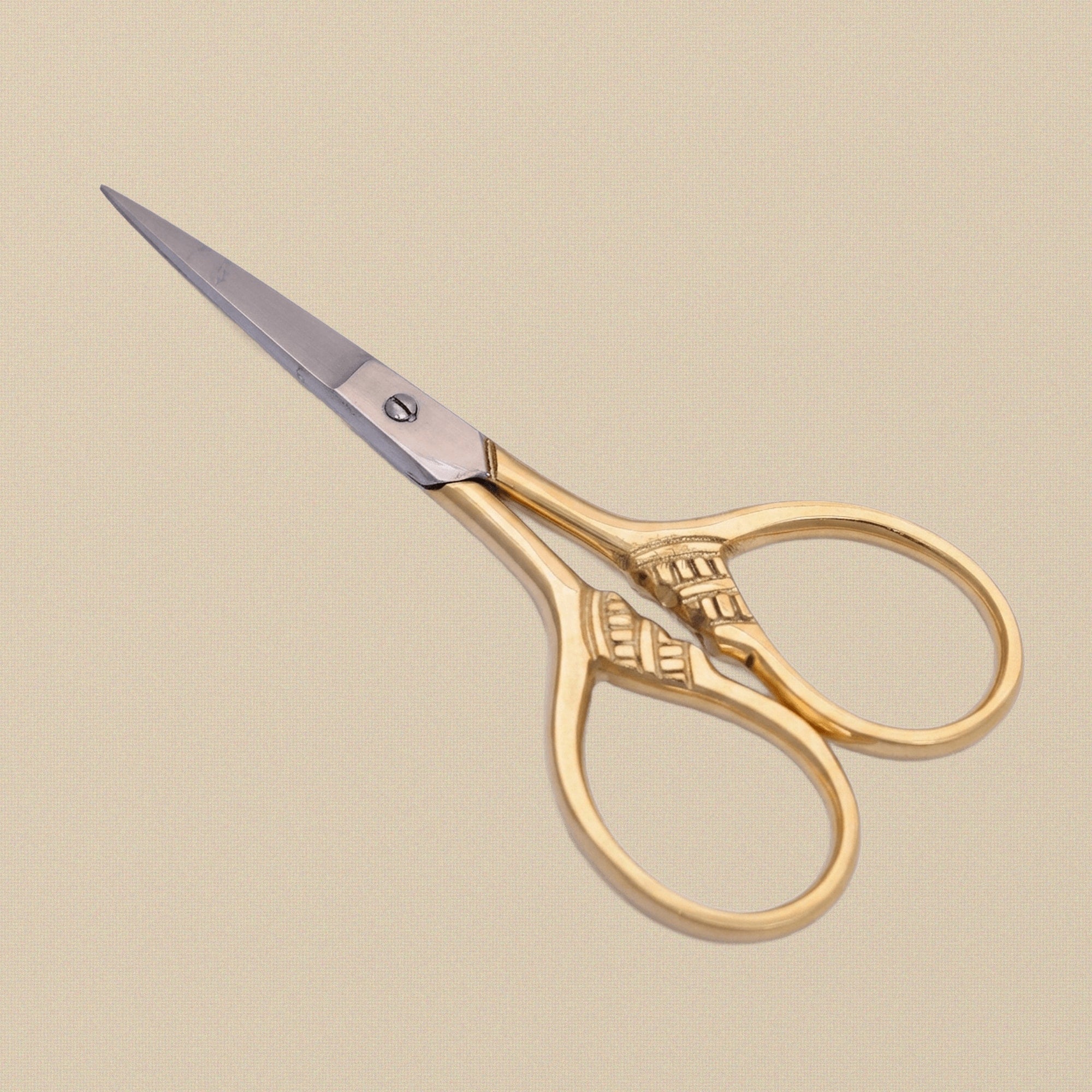 Gold-plated embroidery scissors with an angular floral handle design, shown closed against a white background.