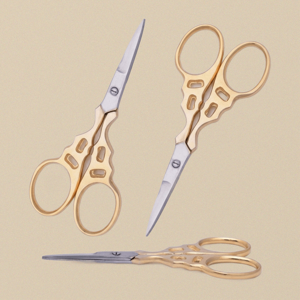 Gold-plated decorative embroidery scissors with ornate handles, shown closed on a white background.