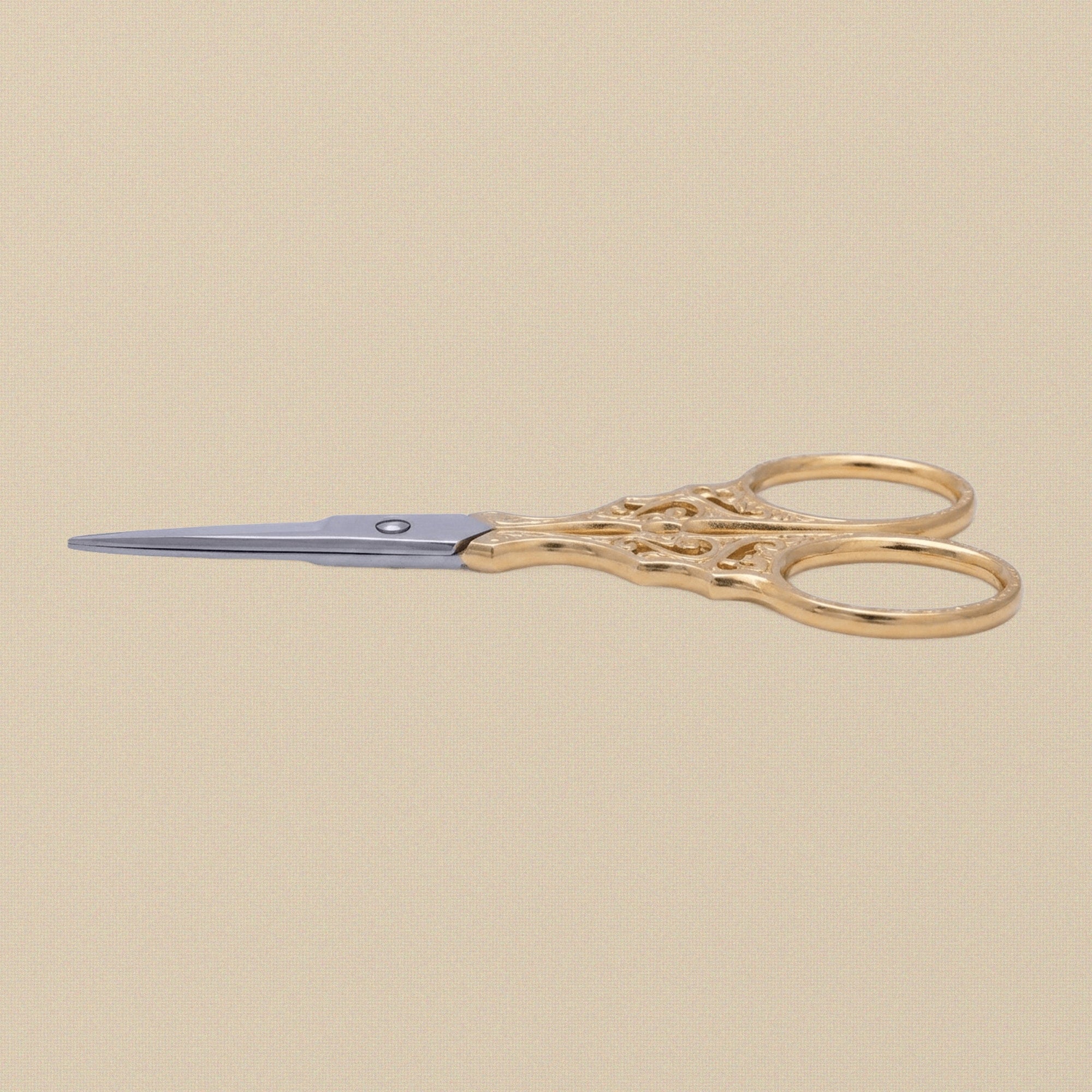 Close-up of the ornate, cut-out handles of the gold-plated embroidery scissors.