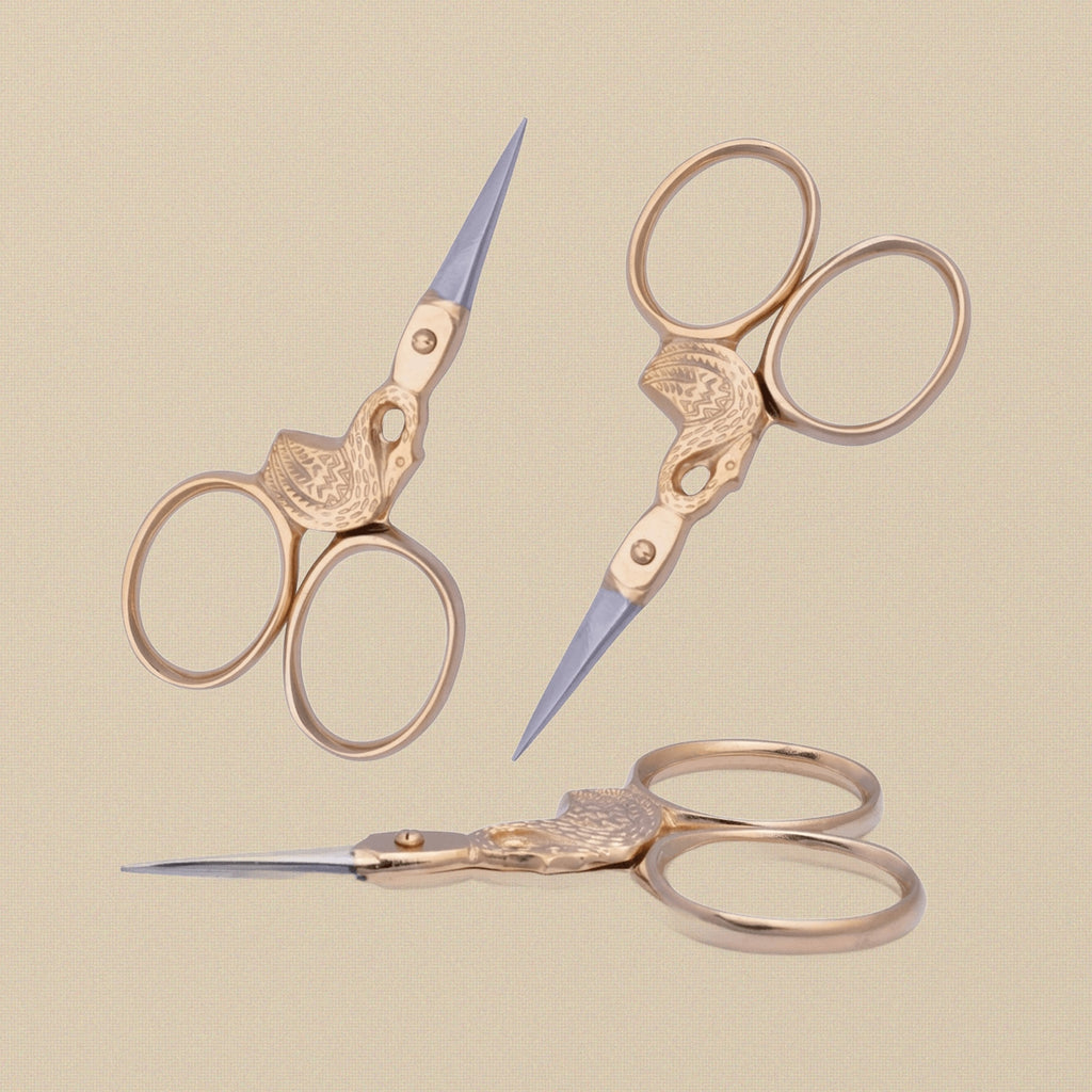 Gold-plated swan-shaped embroidery scissors on a white background.