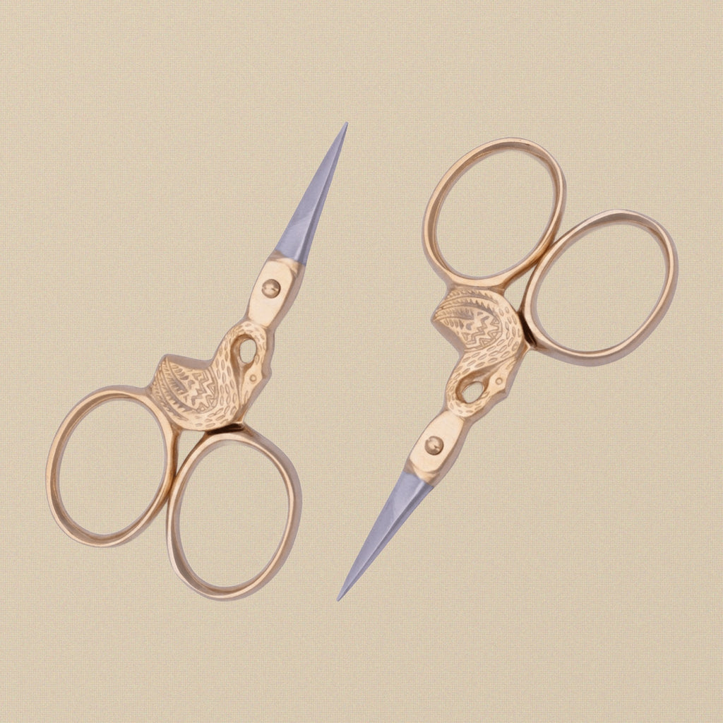 The swan scissors held in hand to show scale and the elegant handle design.