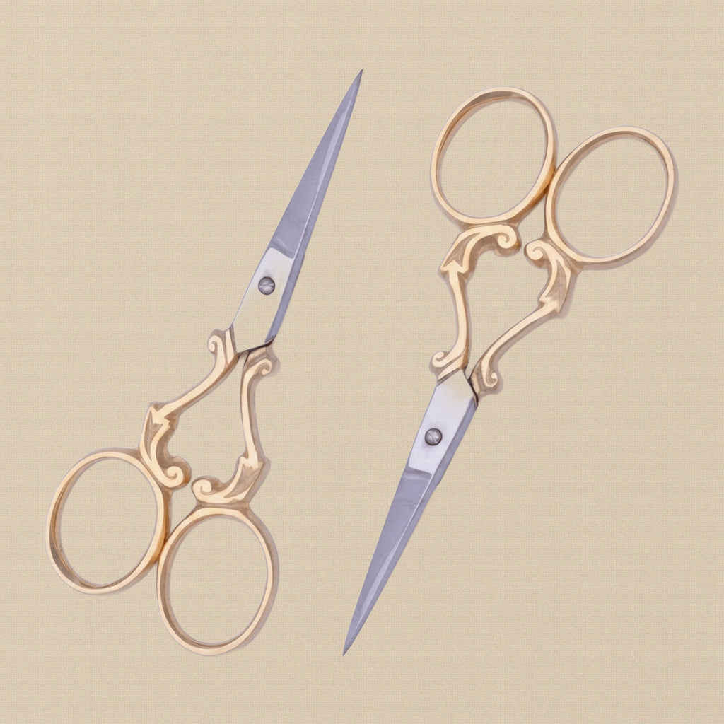 A pair of 4-inch gold-plated embroidery scissors with ornate vine-scroll handles, shown closed against a white background.