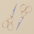 A pair of 4-inch gold-plated embroidery scissors with ornate vine-scroll handles, shown closed against a white background.