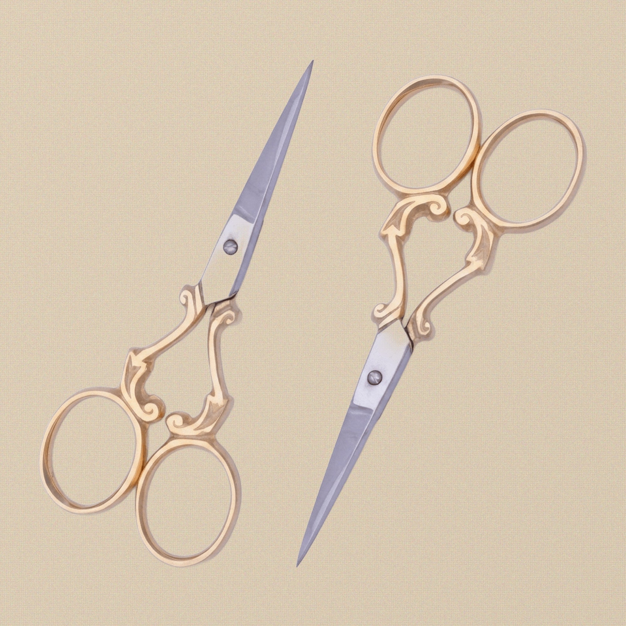 A pair of 4-inch gold-plated embroidery scissors with ornate vine-scroll handles, shown closed against a white background.