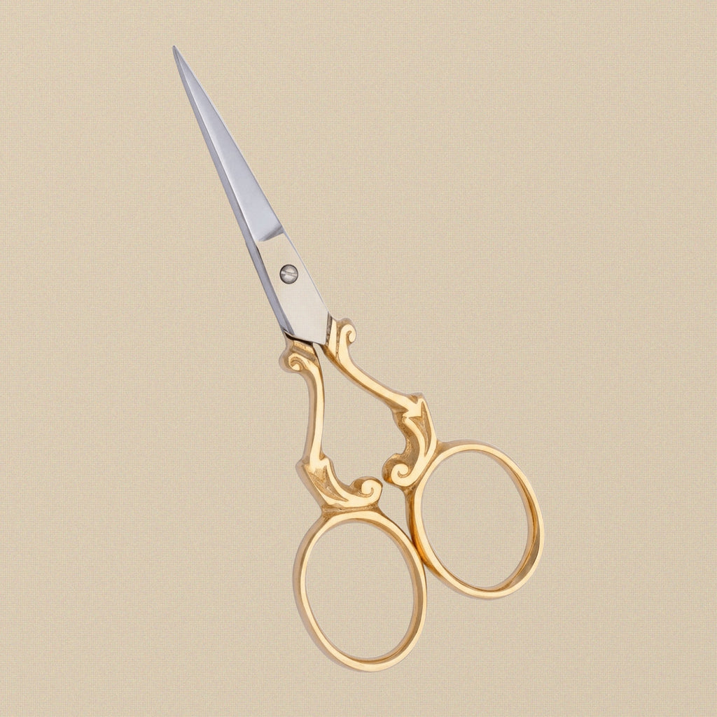 Detail shot of the fine, sharp points and gold-plated finish of the ornate embroidery scissors.