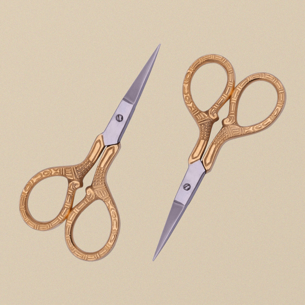 Gold-plated 4-inch embroidery scissors with engraved handles, shown closed on a white background.