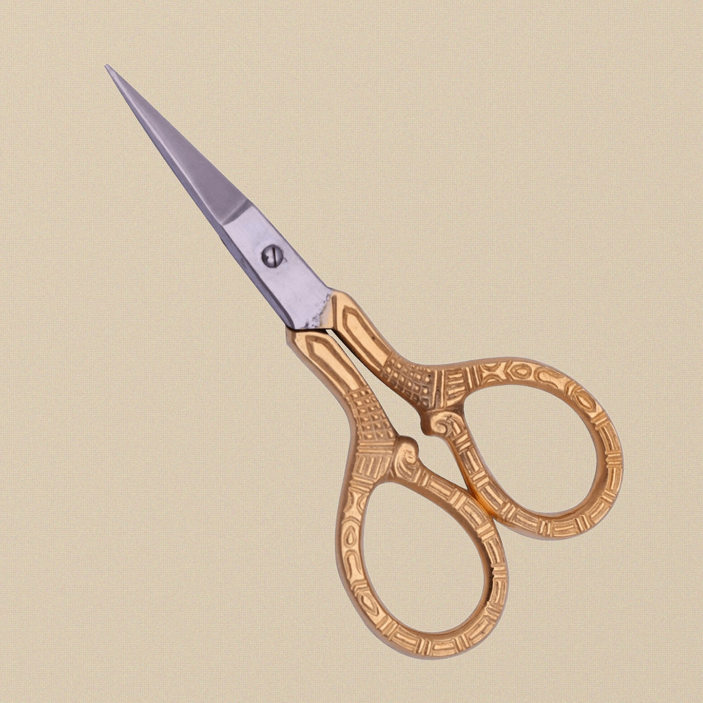 Close-up of the engraved print pattern on the handles of the gold-plated detail scissors.