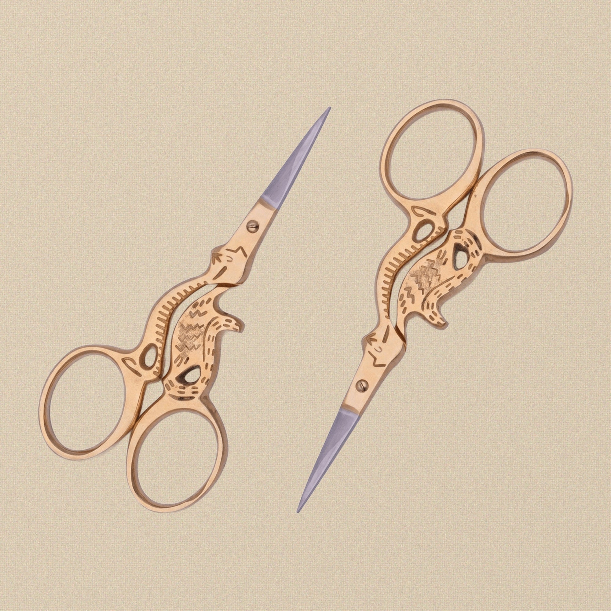 Gold-plated embroidery scissors with handles shaped like a sitting cat, shown closed on a white background.