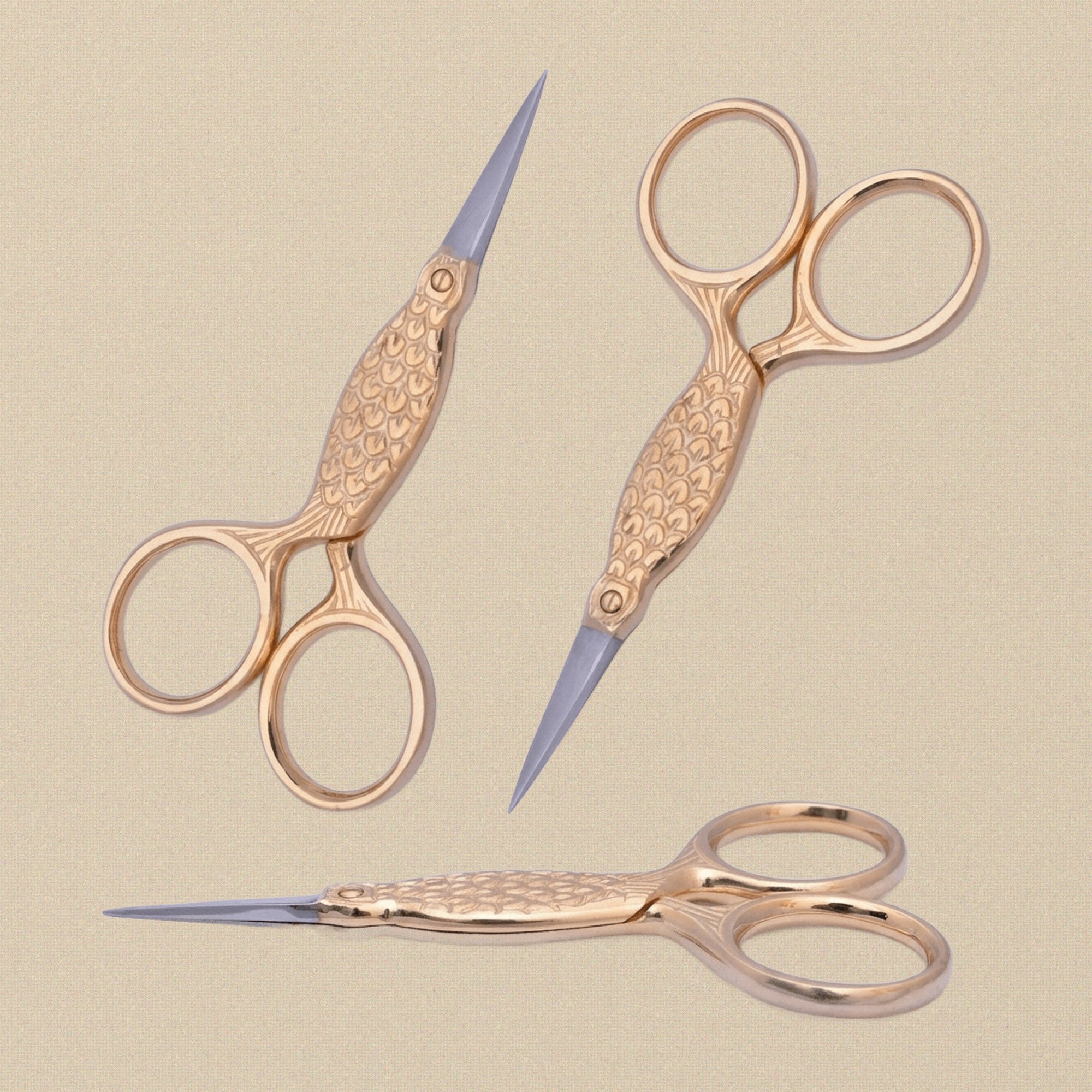 Gold-plated fish-shaped embroidery scissors on a white background.
