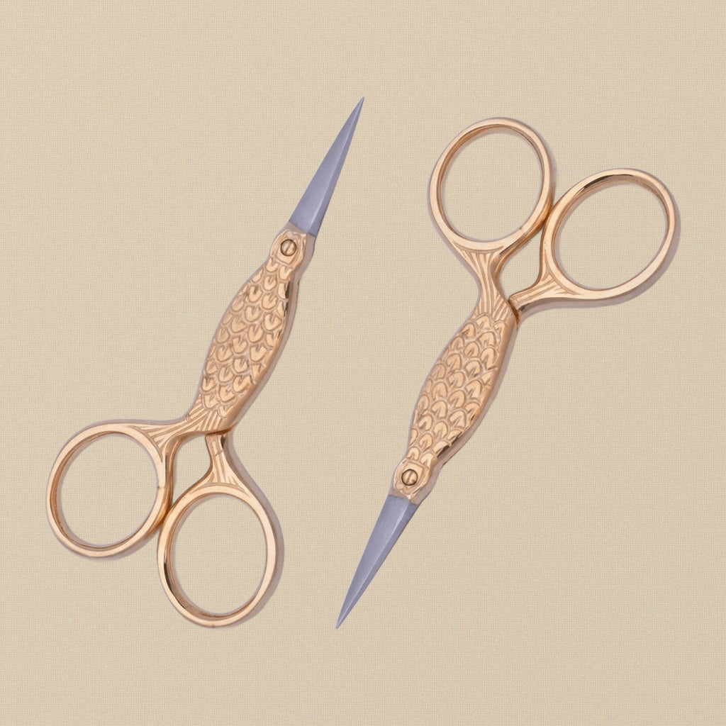 The 3.5-inch gold-plated fish scissors held in hand to show scale.