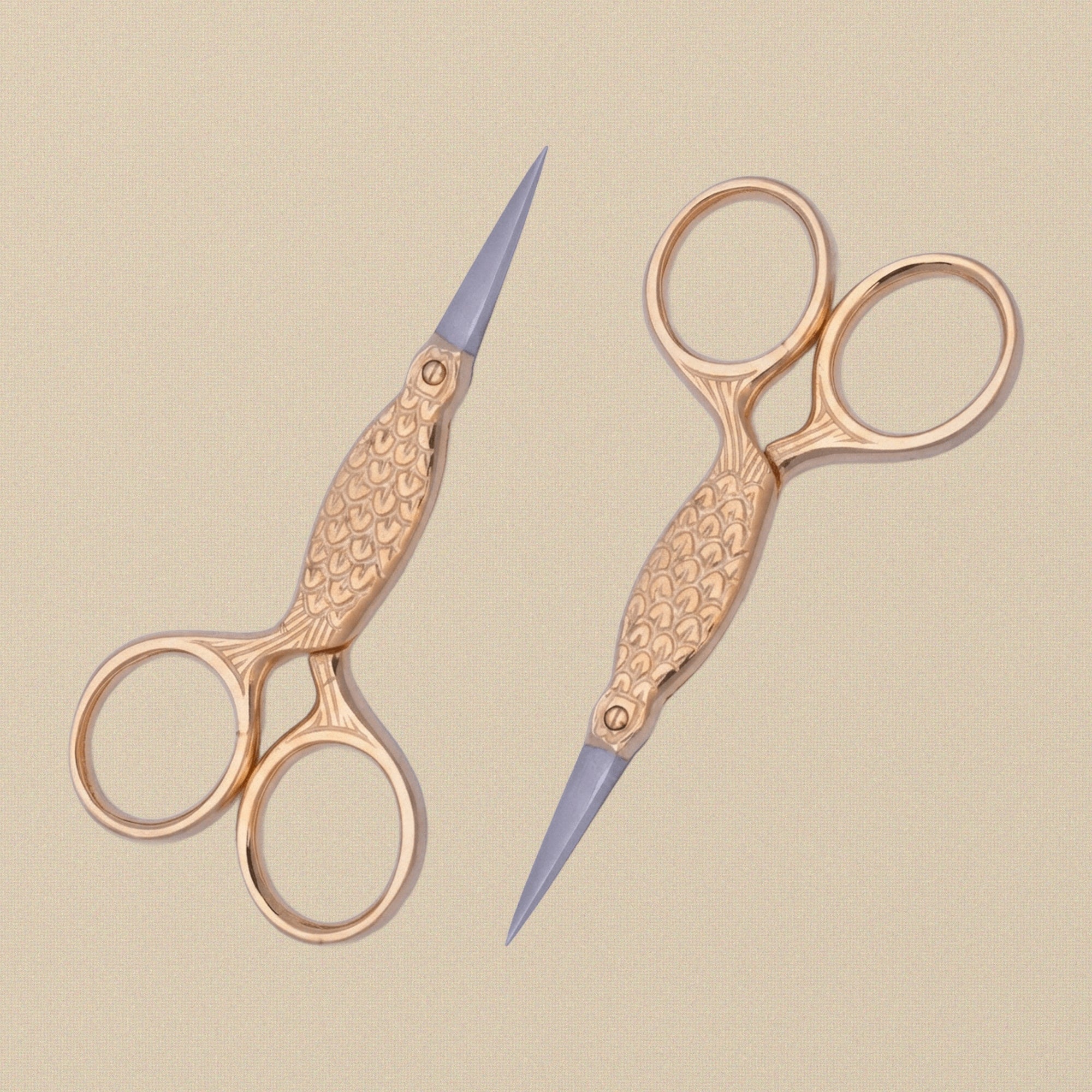 The 3.5-inch gold-plated fish scissors held in hand to show scale.