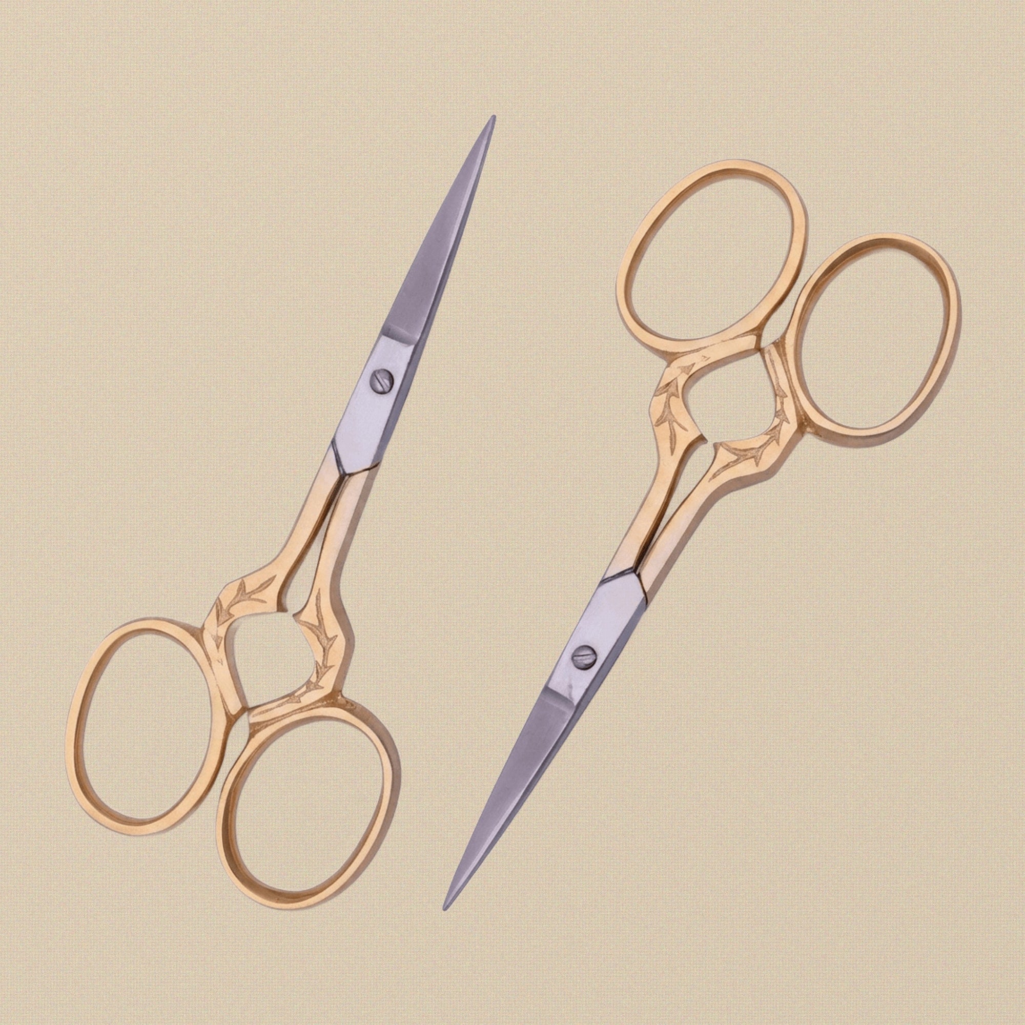 Gold-plated embroidery scissors with leaf-shaped handles, shown closed on a white background.