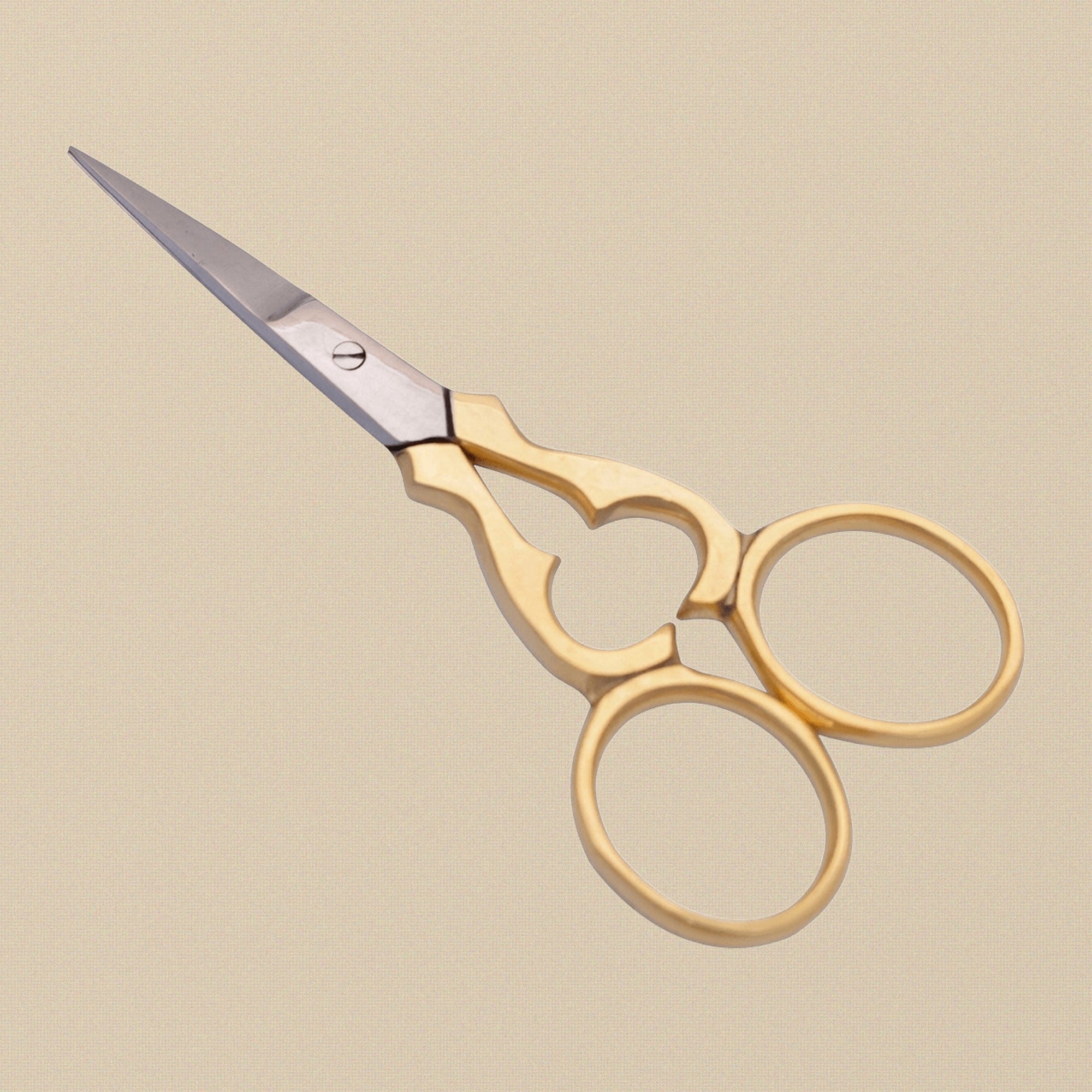 Ornate gold-plated embroidery scissors with floral pattern handles on a white background.